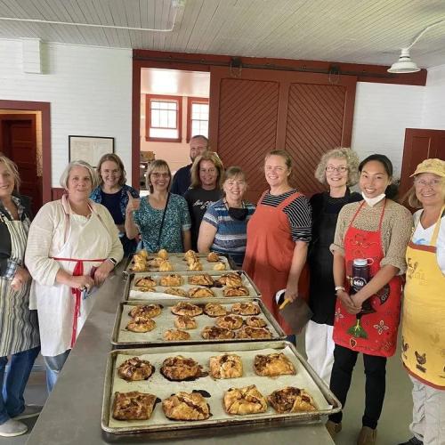 group standing around 3 trays of pies