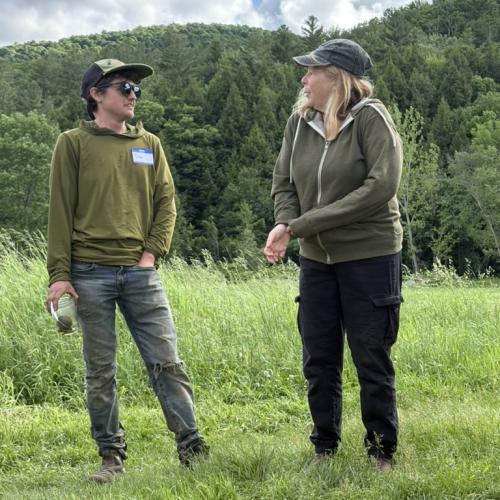 Stoni Tomson of New Tradition Farm and Sarah Jane Williamson of Jubilee Farm stand in a field chatting with Land Together Learning Network participants about their experiences sharing land in Huntington