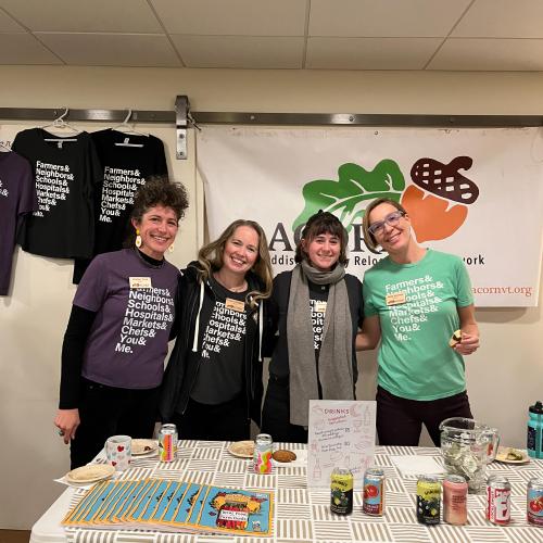 ACORN staff & board members stand smiling behind a beverage table at the 2025 Annual Meeting