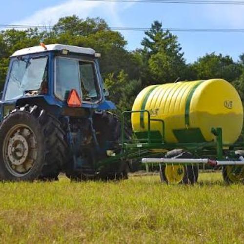 A blue tractor is shown pulling a trailer with a urine fertilizer tank